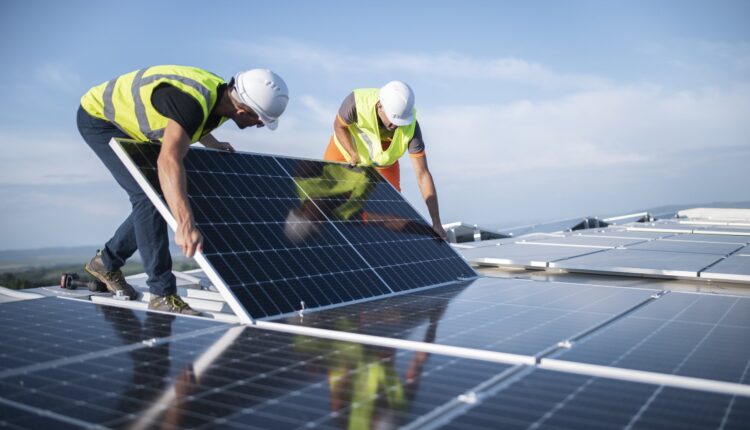 Two engineers installing solar panels on roof.